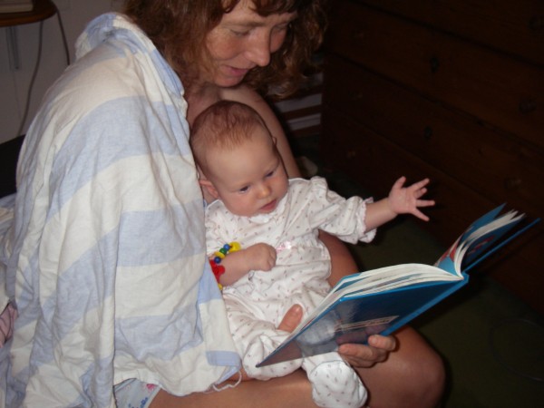 Mommy reading a book with Leilani sitting on her lap and looking at the pictures.